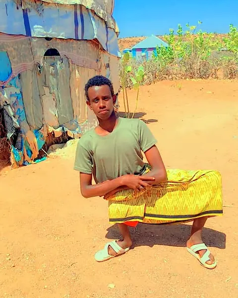 A young man sitting outside his home