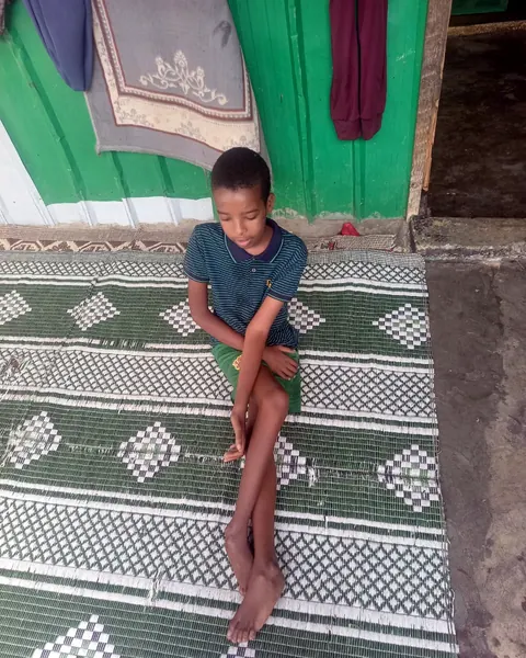 A boy sitting on a green mat