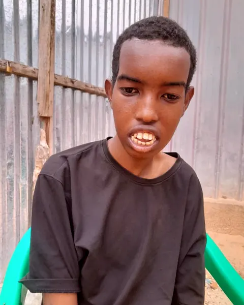 A boy in a black shirt sitting on a chair