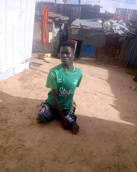 A young man in a green shirt kneeling in a yard
