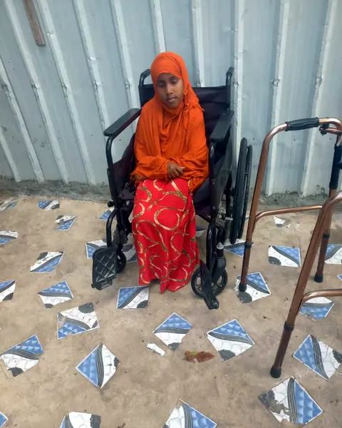 A girl in a wheelchair with a walker beside her